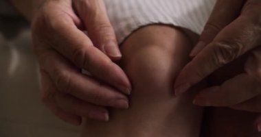Yaşlı bir kadının diz eklemi zedelenmiş. Emeklilerin ellerinin popliteal ya da sinoviyal kisti ovalarken, dizlerinin arkasında sıvı dolu bir şişlik oluşur. Popliteal kist, sıvı.