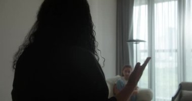 Aile içi şiddet. Bir anne, kanepede oturan çocuğuna doğru elini kaldırır, yüzünü kapatır ve korkuyla gözlerini kapatır. Anne öfkeyle genç kızına bağırır. 4K içinde video