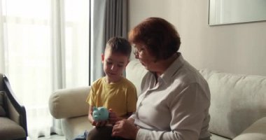 Sevecen, mutlu, yaşlı bir kadın büyükanne ve sevimli küçük bir kız torun kalp şeklinde el hareketi yapıyorlar. Kamera kaynaşmasına bak gülüşüne aile sevgisi kavramını gösteriyor, yakın plan portre