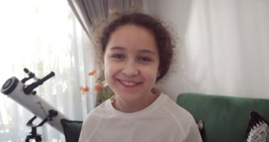 Evdeki kameraya bakarken gülümseyen komik küçük çocuk, webcam 'e bakan sevimli çocuk, online video görüşmesi yapan ya da video kayıt yapan, eğlenen, yakışıklı yüzlü anaokulu çocuğu kanepede oturuyor.