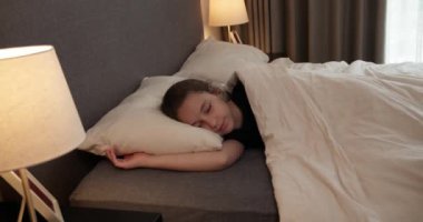 Anne oğluna bakıyor. Yatakta uyuyan bebek. Yan yatmış uyuyan çocukla yüzleş. İzleme, gece yarısı uyuyan bebeği vurdu. Küçük erkek bebek beşiğinde tatlı tatlı uyuyor ve uykusunda gülümsüyor.