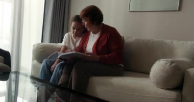 Mutlu aile ilişkileri. Birlikte masal okumaktan zevk alıyoruz. Sevimli kızıl saçlı küçük kız gülümsüyor ve sevgi dolu büyükannesiyle hafta sonunu evde geçirdiğini söylüyor. 4K 'da yavaş çekim