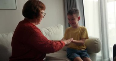 60 yaşındaki büyükannesi ve torunu, kimin önce diğer ellere dokunabileceğini görmek için şakayla karışık yarışıyorlar. Kahkahaları ve eğlenceleri evlerinde kanepede otururken rahat ve mutlu bir atmosfer yaratıyor. 4K