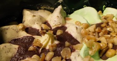 Vanilyalı dondurma ve fıstık serpiştirilmiş şam fıstığının kaygan görüntüsü. Çikolata parçalı, fındıklı ve vişneli dondurma. Yiyecek konsepti