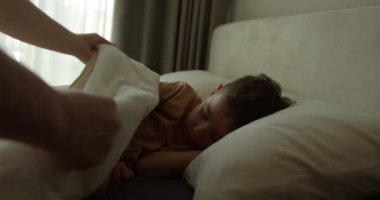 Anne oğluna bakıyor. Yatakta uyuyan bebek. Yan yatmış uyuyan çocukla yüzleş. İzleme, gece yarısı uyuyan bebeği vurdu. Küçük erkek bebek beşiğinde tatlı tatlı uyuyor ve uykusunda gülümsüyor.