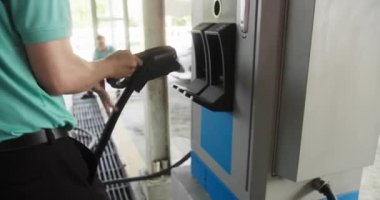 Bu resim, şarj istasyonuna sıkıca bağlı olan elektrikli bir aracın detaylı bir yakın çekimini gösterir.