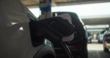 Bu görüntü, şarj cihazına güvenli bir şekilde bağlı olan elektrikli bir aracın yakın çekimini gösteriyor.