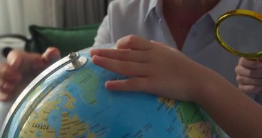 Büyükannesiyle birlikte çocuk, gün batımında evde otururken ders çalışıyor. Günbatımında çocuk, Globe ve büyüteçle sevimli çocuk, okul çocuğu için teknoloji, çocuk dünyaya bakıyor.