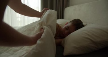 Anne oğluna bakıyor. Yatakta uyuyan bebek. Yan yatmış uyuyan çocukla yüzleş. İzleme, gece yarısı uyuyan bebeği vurdu. Küçük erkek bebek beşiğinde tatlı tatlı uyuyor ve uykusunda gülümsüyor.