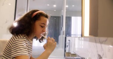 Beyaz dişli şirin beyaz çocuk evde izole edilmiş aynaya bakıyor. Yaşam tarzı. Portre mutlu küçük bir çocuk banyoda dişlerini fırçalıyor ve gülümsüyor. Çocuklar günlük sağlık hizmeti rutini. 4K