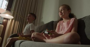 Oğlan ve Kız, Kanepe Arkadaşları 'nda oyun oynamak için telefon kullanıyor. Çocuklar kanepede otururken TV 'de video oyunu oynuyorlar. Bir erkek ve bir kız TV 'de video oyunu oynuyorlar..