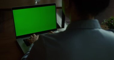 Modern iş yerinde uzaktan çalışan bir kadın bilgisayarda daktilo kullanıyor. Bilinmeyen kız yönetici klavye kroma tuşlu bilgisayarda kapalı alanda yazıyor. Yeşil ekran defteri kullanan iş kadını.