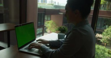 Modern iş yerinde uzaktan çalışan bir kadın bilgisayarda daktilo kullanıyor. Bilinmeyen kız yönetici klavye kroma tuşlu bilgisayarda kapalı alanda yazıyor. Yeşil ekran defteri kullanan iş kadını.