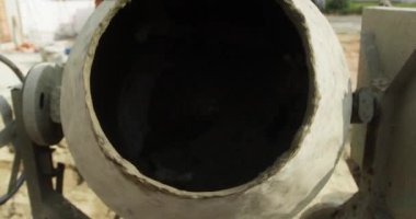 Erkek inşaat işçisi çimento karıştırıcı kullanarak yavaş çekimde beton karışımı yapıyor..