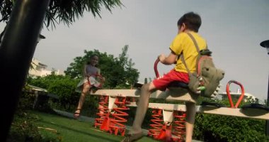 Happy Children parkta sallanıyor. Mutlu bir oğlan ve mutlu bir kız parkta salıncakta sallanıyorlar gökyüzüne karşı.