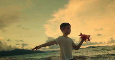 Kumsalda koşan oyuncak uçaklarla oynayan mutlu beyaz çocuklar. Küçük çocuklar, erkek ve kız kardeşler plajda koşuyorlar, oynuyorlar, aile tatili yapıyorlar. Küçük çocuklar için kumsal tatili kavramı. Oynayan çocuklar