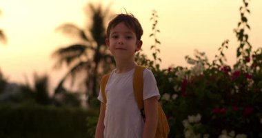 Yakışıklı bir okul çocuğunun portresi, gülümseyen bir okul çocuğu, sırt çantalı küçük bir çocuk, güneşli bir sokakta tek başına duruyor, yakışıklı bir birinci sınıf öğrencisi. 4 bin.