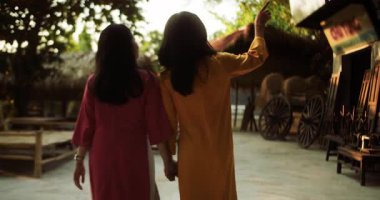 Vietnam 'daki Nha Trang şehrinde geleneksel giysileri içinde genç turistler yürüyor. Eski şehrin varoşlarında ulusal elbise ve şapkalarla dolaşan iki kız..