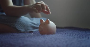 Çocuk parasını sayıyor ve kumbaraya koyuyor. Liseli kız pembe domuz kumbarasına bozuk para atıyor. Bankacılık güvenliğinin domuz kumbarasındaki madeni paralar. Finansal tasarruflar. Mali güvencedeki çocuklar