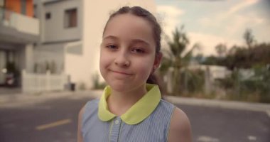 Küçük Çocuk Kız 'ın Yaz Günü' nde Cadde 'de duran kameraya baktığı portre. Genç Mutlu Düşünen Meraklı Çocuk Dışarıda Kameraya Yakından Bakıyor. Yüz Gözleri Komik Düşünceli Çocuk. 4K