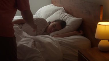 Anne oğluna bakıyor. Yatakta uyuyan bebek. Yan yatmış uyuyan çocukla yüzleş. İzleme, gece yarısı uyuyan bebeği vurdu. Küçük erkek bebek beşiğinde tatlı tatlı uyuyor ve uykusunda gülümsüyor.