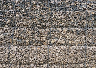 Gabion with heaps of small stones in a grid as the city or garden decoration, textured background