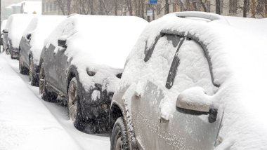 Row of cars covered by snow during heavy snow storm in the city clipart