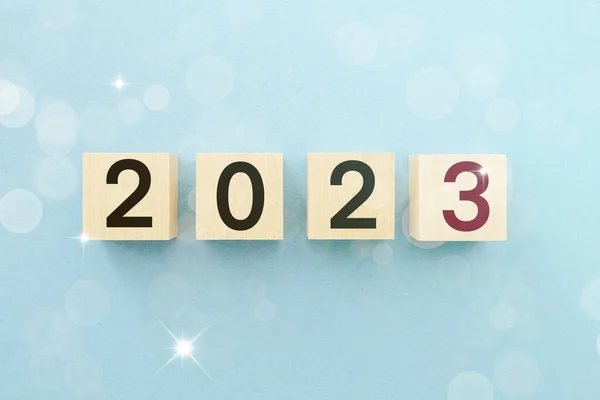 2023 New Year picture. Wooden cubes on blue background with bokeh with numbers 2023. Business concept picture with christmas theme.