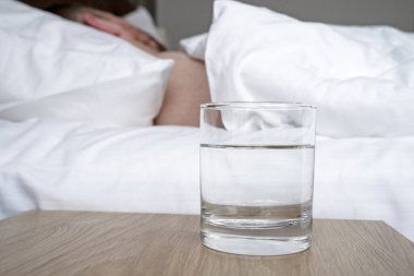 Ahşap masada su ve bir odada uyuyan bir insan.