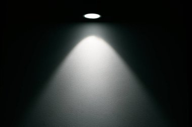 Gece vakti karanlık odada yuvarlak lambadan gelen ışık huzmesi
