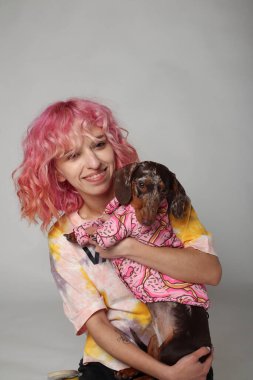 Pembe saçlı bir kız köpekle gülümsüyor. Arkadaşlar, Marble Dachshund. Beyaz arkaplan