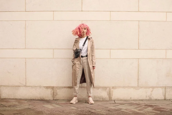 ピンクの髪をしたスタイリッシュな女の子のポートレート撮影 ベージュの色合い 春と夏の傾向2023 白のTシャツとベージュのパンツとベージュのトレンチコート 黒小さなベルトバッグ — ストック写真