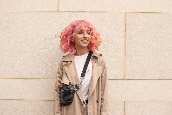 ピンクの髪をしたスタイリッシュな女の子のポートレート撮影 ベージュの色合い 春と夏の傾向2023 白のTシャツとベージュのパンツとベージュのトレンチコート 黒小さなベルトバッグ — ストック写真