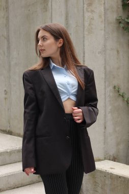 Tarz sahibi bir kızın portresi. Koyu gölgeler. 2023 ilkbahar ve yaz trendi. Klasik ceket ve siyah pantolon. Mavi gömlek. İş merkezi. Ofis işi