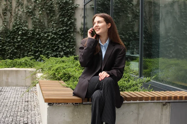 一个时髦女孩的肖像拍摄 在讲电话 2023年春季和夏季的趋势 女商人经典的夹克和黑色裤子 蓝色衬衫 商务中心 办公室工作 — 图库照片
