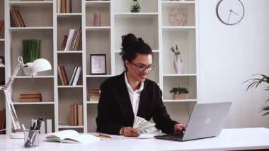 Para içinde yüzen Latin Amerikalı bir kız, para kazandığı için mutlu. Başarı kariyeri, piyango oyunu galibi, büyük gelir, ofis çalışma masasında zenginlik. Uzaktan kumandalı. Ofis, resmi kıyafetler, laptop..
