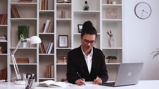 拉丁美洲女孩在办公室工作 他在协议上签了字 并对着摄像机笑了 电子商务 自由撰稿人 办公室 正式服装 手提电脑 — 图库视频影像