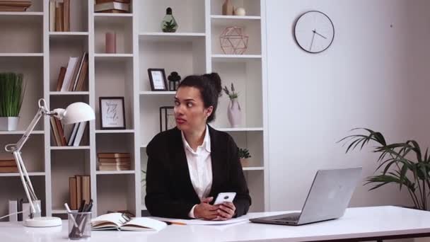 西班牙裔女孩在办公室里用手机玩游戏 而没人在看 电子商务 自由撰稿人 办公室 正式服装 手提电脑 — 图库视频影像