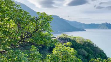 Guatemala 'daki Atitlan Gölü üzerinde yükselen ve arka planda volkanlar bulunan 4K video görüntüsü 