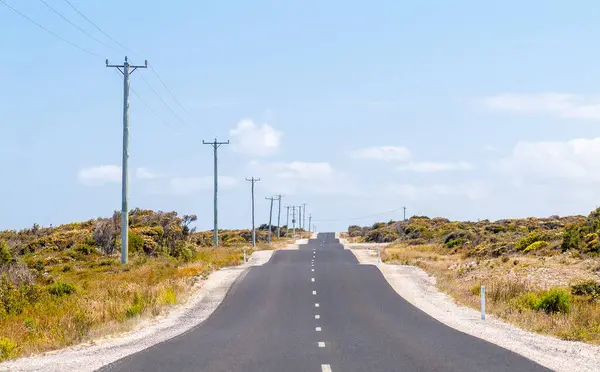 重度の不規則なまたはバンプの道は オーストラリアのタスマニアの夏の空の下で電力線と熱の危険との距離に伸びます — ストック写真