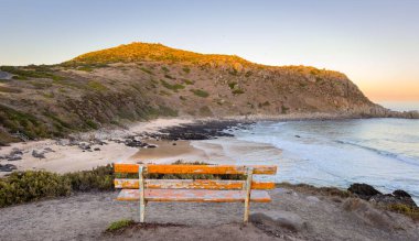 Bench at the Petrel Cove lookout with Rosetta Head or The Bluff on the Fleurieu Peninsula in South Australia at sunset clipart