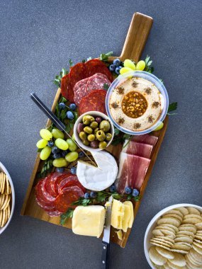Tahtada çeşitli et, meyve ve peynir tabakları bulunan bir şarküteri veya peynir tabağının üst görüntüsü