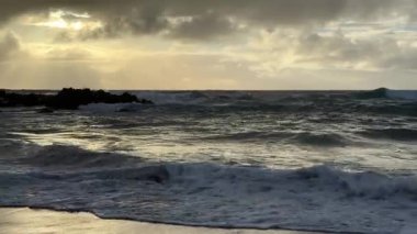Gün doğumunda Stradbroke Adası 'nda denize bakan yumuşak dalgalar kıyıya doğru süzülüyor.