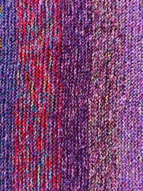 Ayrıntılı arkaplan dokusu olarak jartiyer dikişi kullanılarak örülmüş farklı renklerde yün iplik.