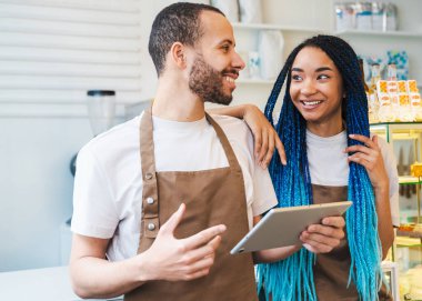 Elinde tablet olan mutlu erkek barista garsonla konuşuyor. Kahve dükkanında online siparişi kabul eden adam.