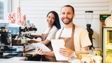 Kahve dükkanında internetten sipariş alırken elinde tablet ve kahve çekirdekleri tutarken mutlu erkek.