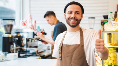Gülümseyen kahve dükkanı sahibi tezgahın önünde dikilirken başparmak hareketi yapıyor. Erkek meslektaşım arka planda kahve yapıyor. Küçük bir iş kuruyorum.