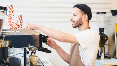 Kahve dükkanında kahve yaparken müşteri siparişini hazırlayan mutlu profesyonel baristanın yan görüntüsü. Küçük kahve işi.