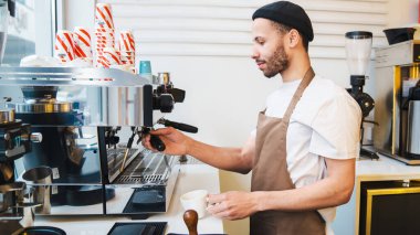 Kahve makinesini kahve yapmak için kullanan sakallı erkek barista. Kahve işçisi kahve hazırlıyor. Hazırlık, servis kavramı