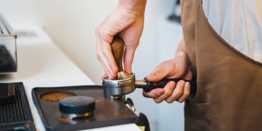 Erkek baristanın elinde tahriş edici tutarken kahve yapmasını yakın çekim, tutacakta öğütülmüş kahve basacak. Kahve hazırlama servisi kavramı